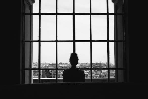Woman staring out from window to city unspalsh image from cristina gottardi