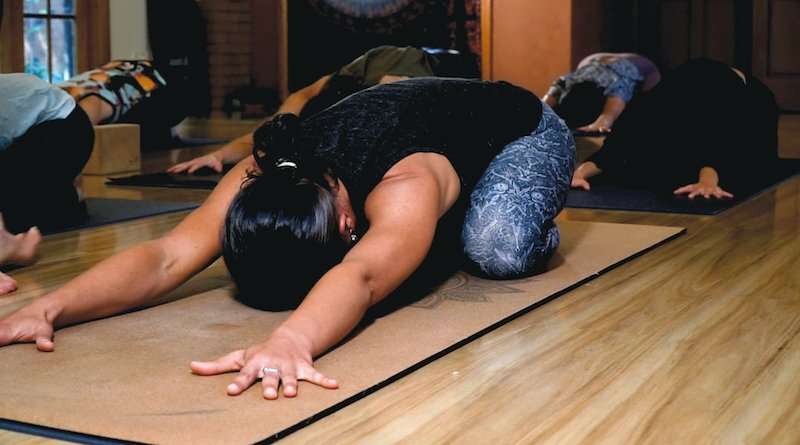 Woman stretches in child pose on sustainable mat, yoga accessory