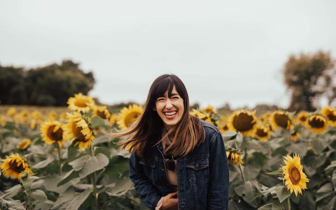 woman laughing in yellow solar plexus sunflower field